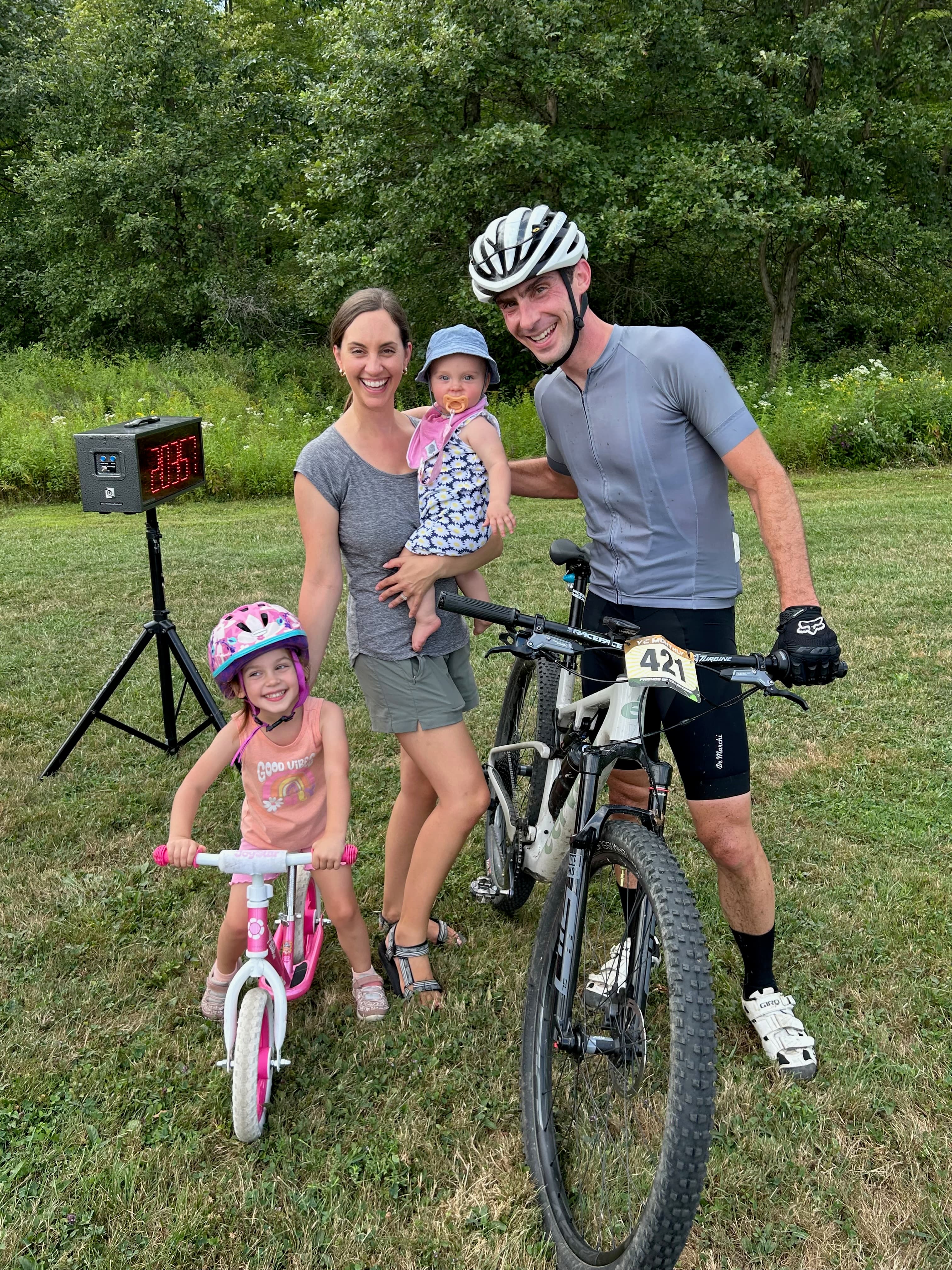 Jim Camut at a race finish with his wife and two daughters, mountain bike alongside.